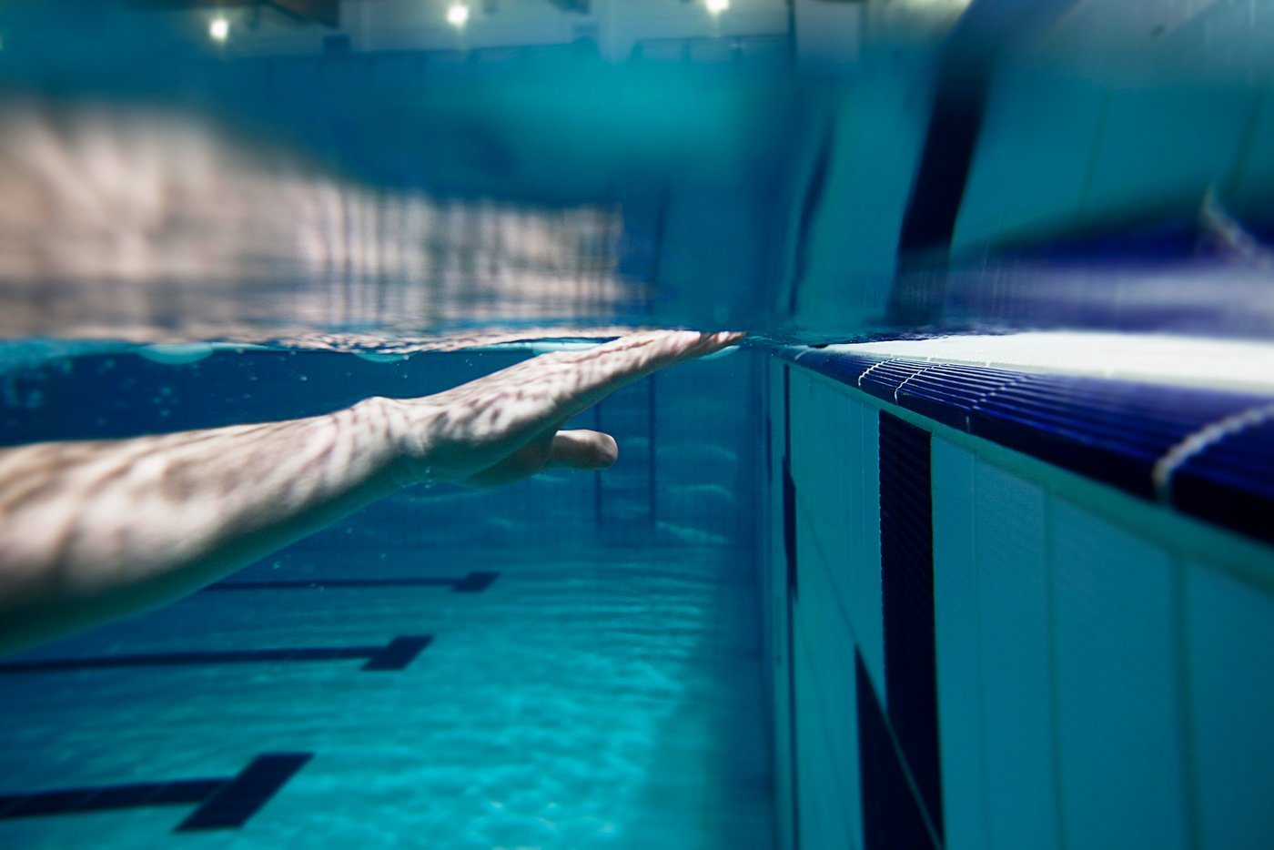 Swimmer's hand reaching forward underwater toward the pool wall